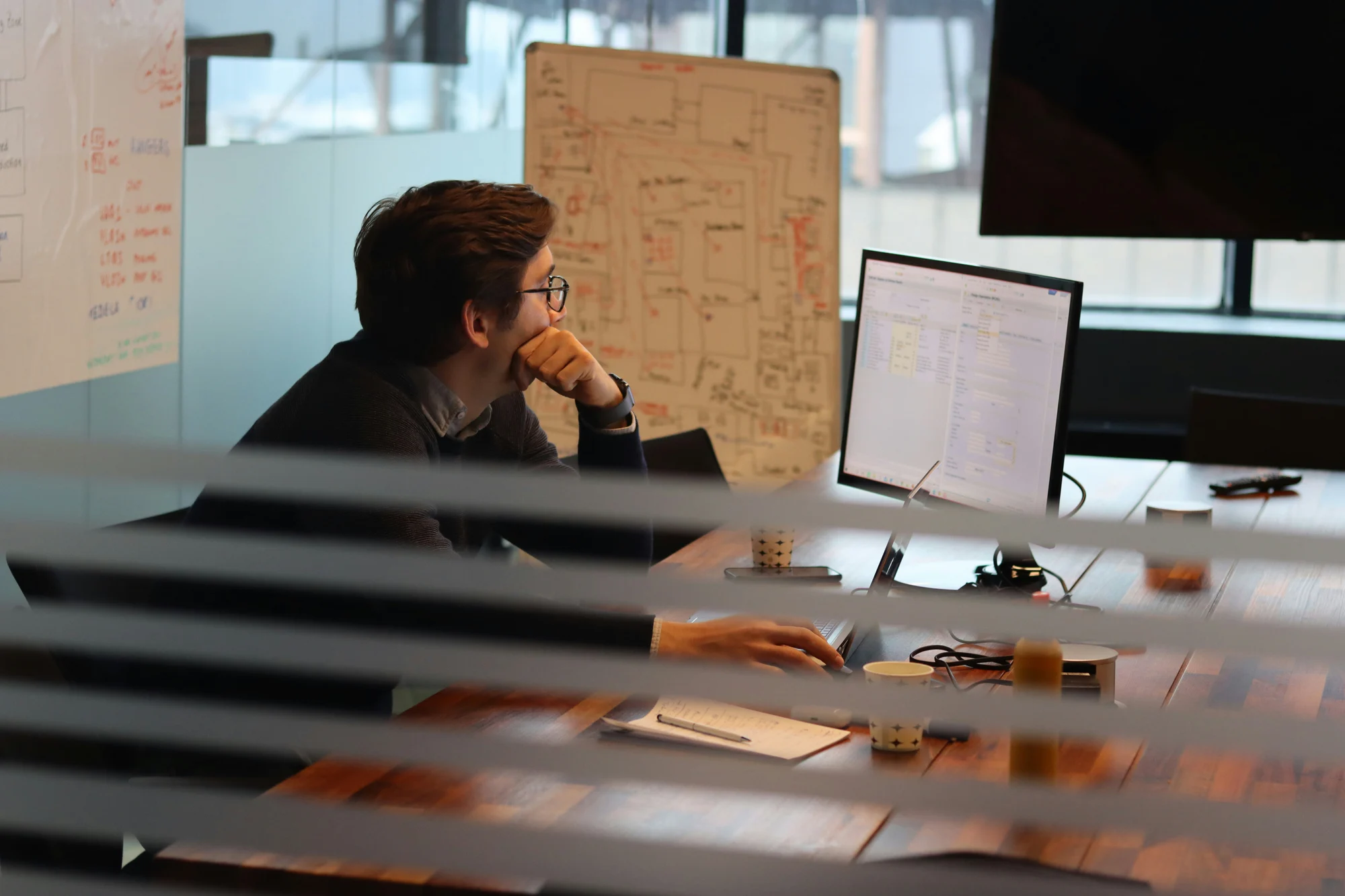 Person analysing a work board with diagrams next to their desk